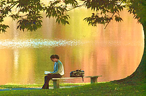 Girl reading by a summertime lake